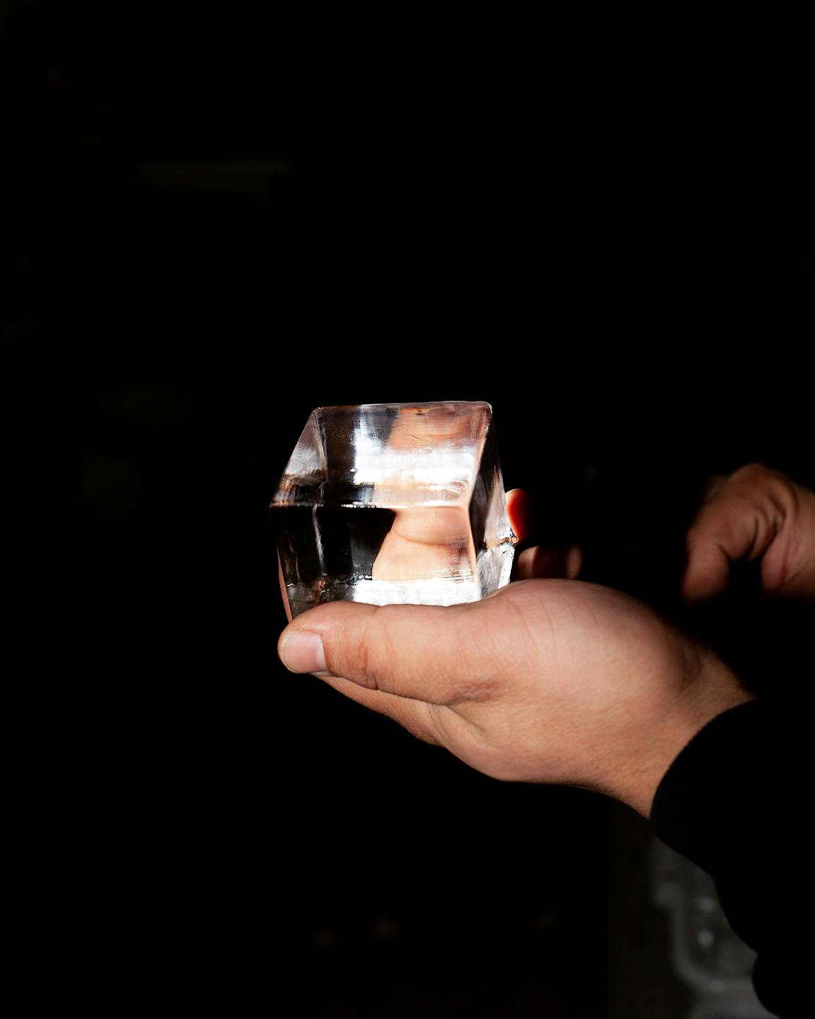 A person holds a perfect cube of ice.